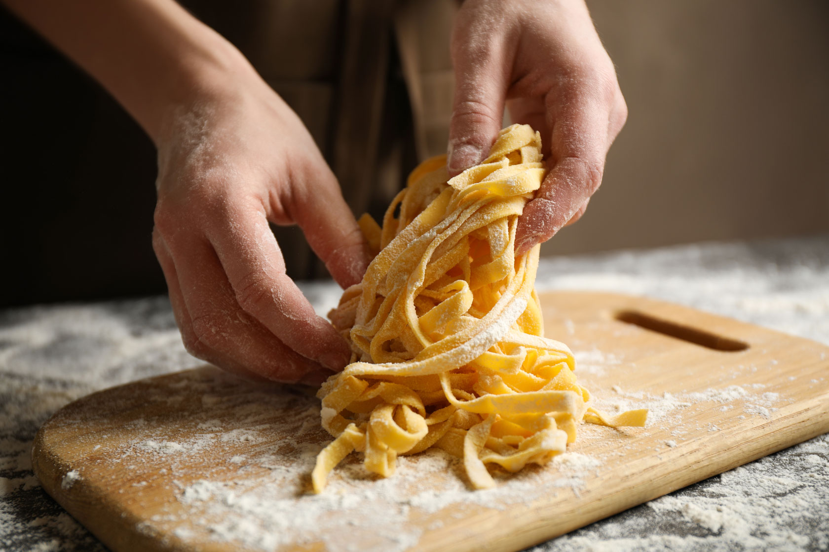 Woman preparing pasta at table, closeup view