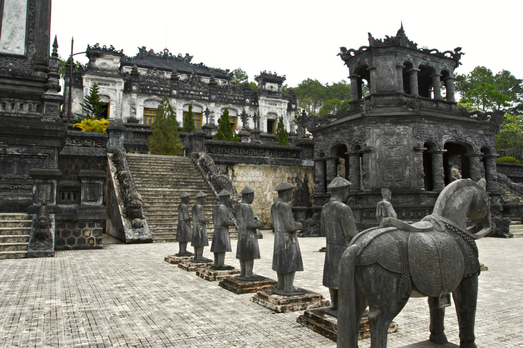 A line of statues stand in front of a staircase at Khai Dinh Tomb.