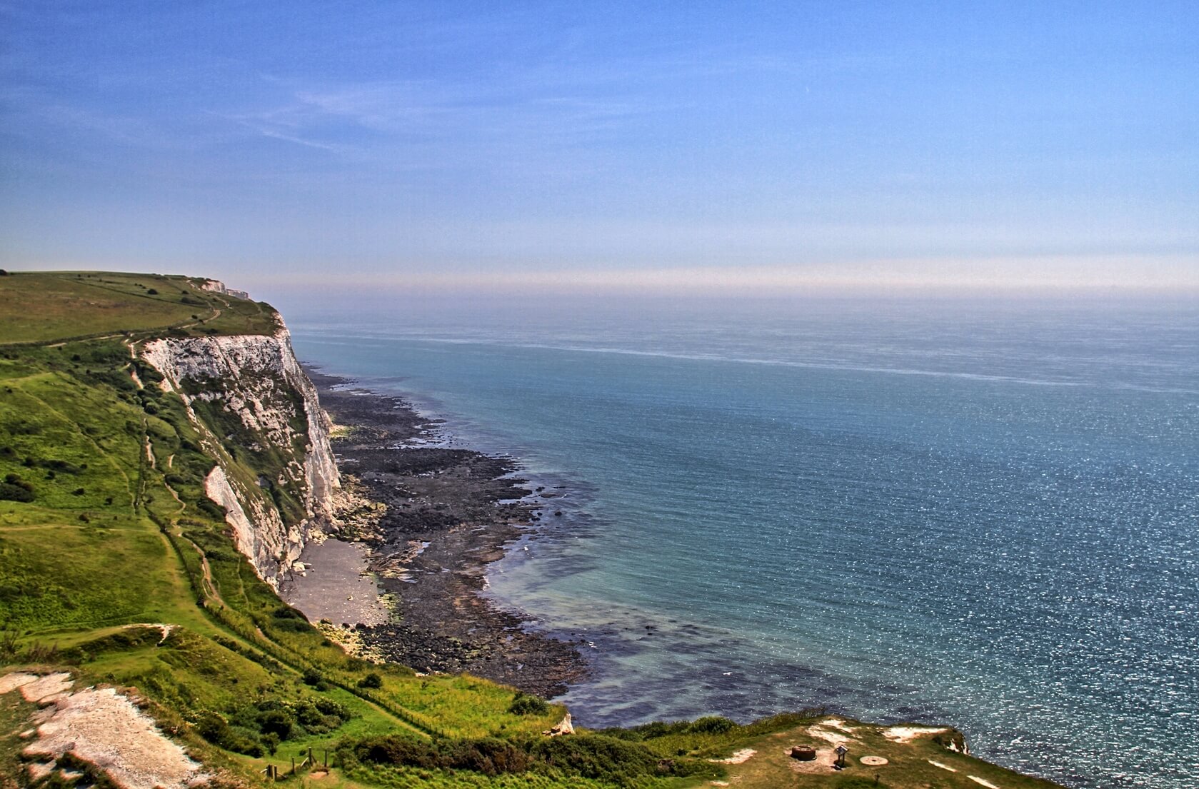 A landscape shot of the famed Cliffs of Dover. The cliffs overlook the ocean, which share the same proportion of the shot. Seabourn cruises visit the Cliffs of Dover