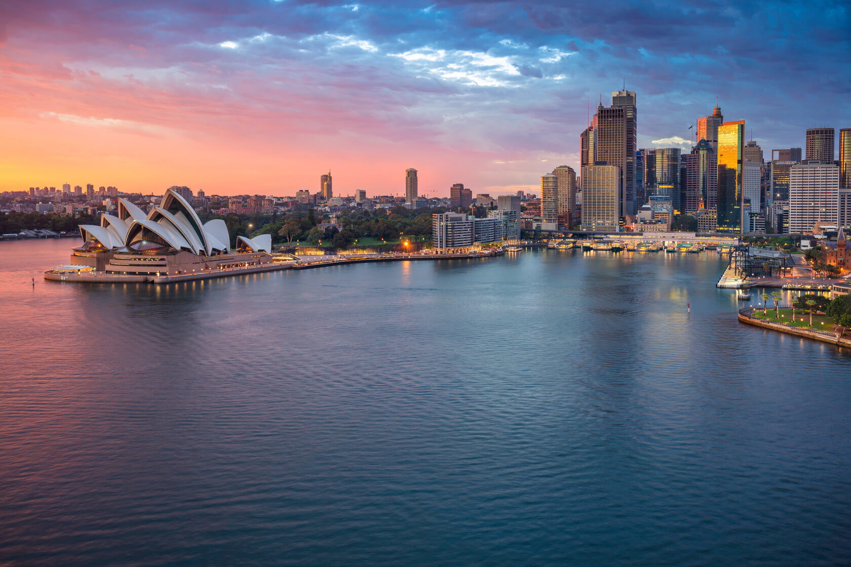 The bright lights from Sydney's Opera House are reflected by the surrounding waterfront. 