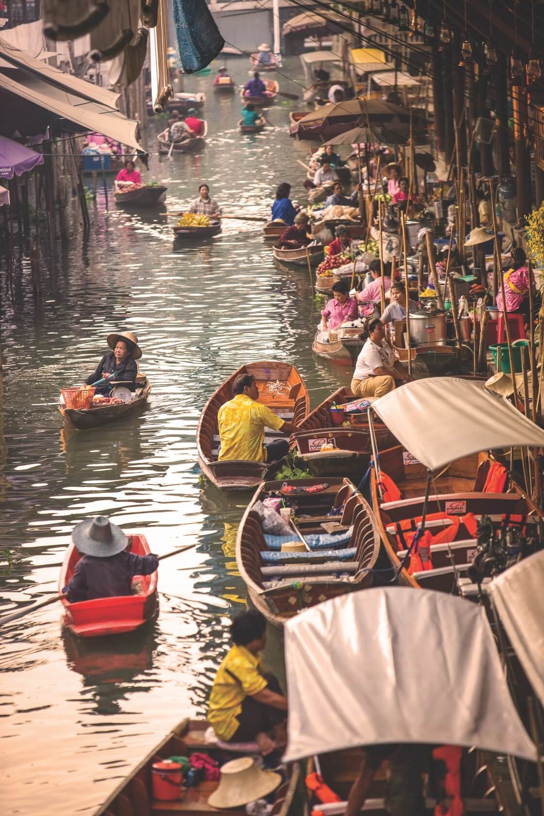 A bust canal market in Bangkok, featuring locals in row boats doing their errands