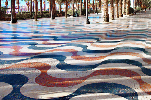 A beautiful promenade in Alicante, paved with white and colored marble to represent waves, is a walkway between the city and the Mediterranean.