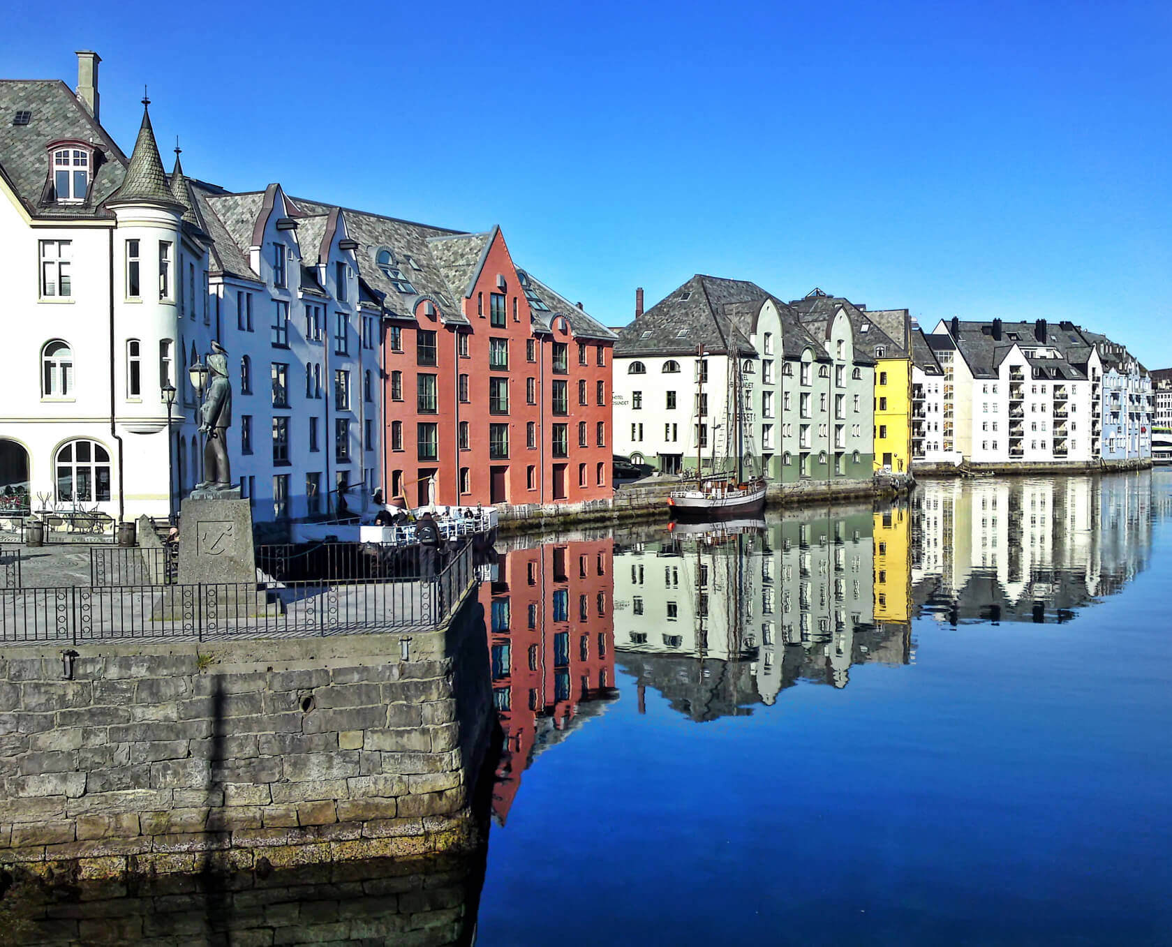 A line of bright colored houses line the water front in Alesund, Norway