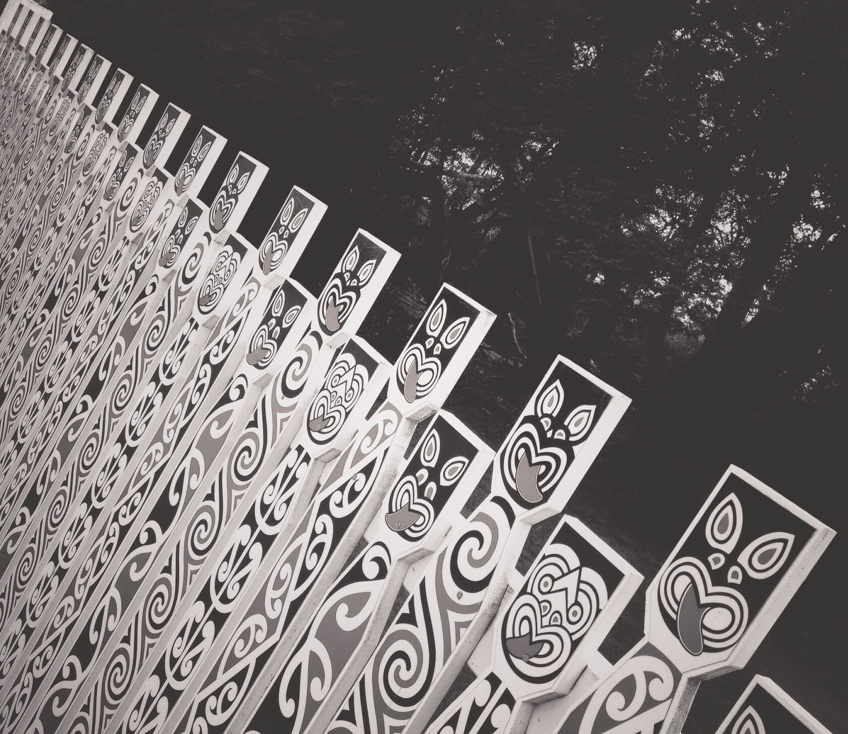 A black and white fence with Maori art is shown